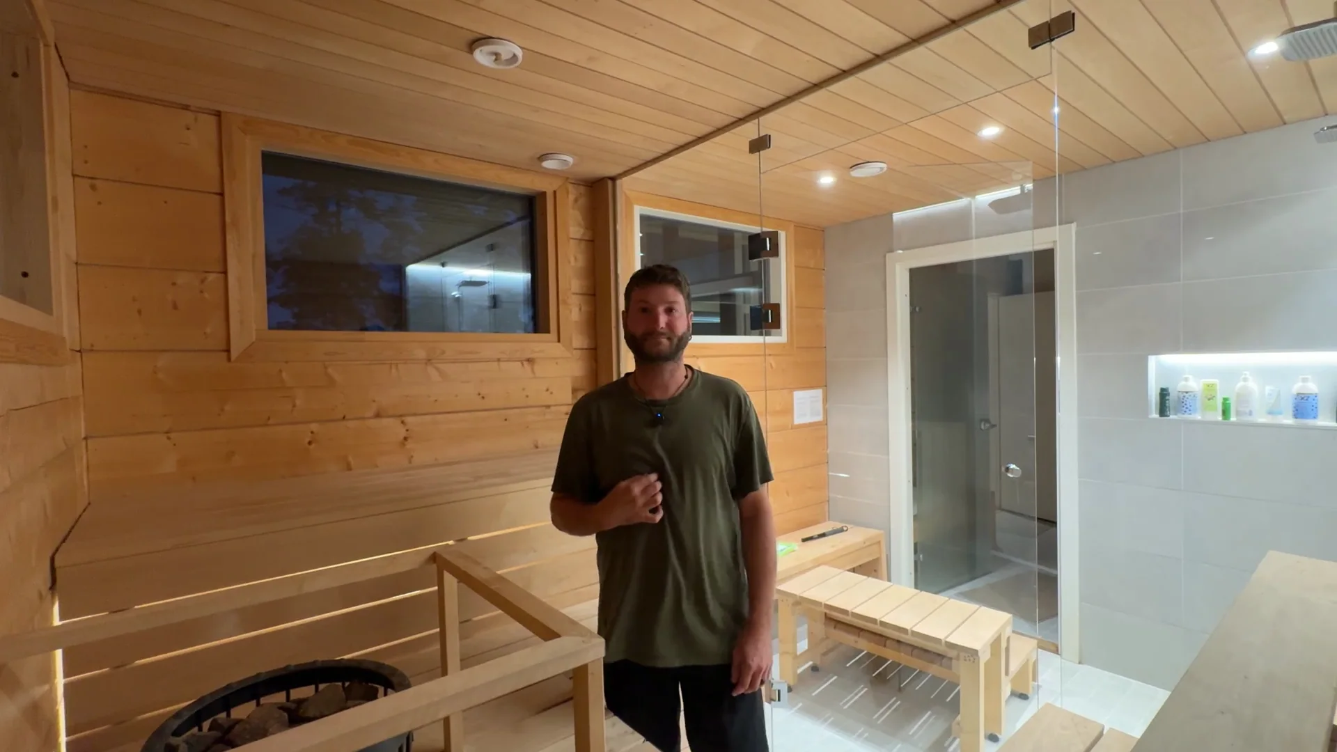 Ben Frizzell standing on the tile in the sauna aisle with the two-step stool lifted out, the glass wall and the shower room behind him