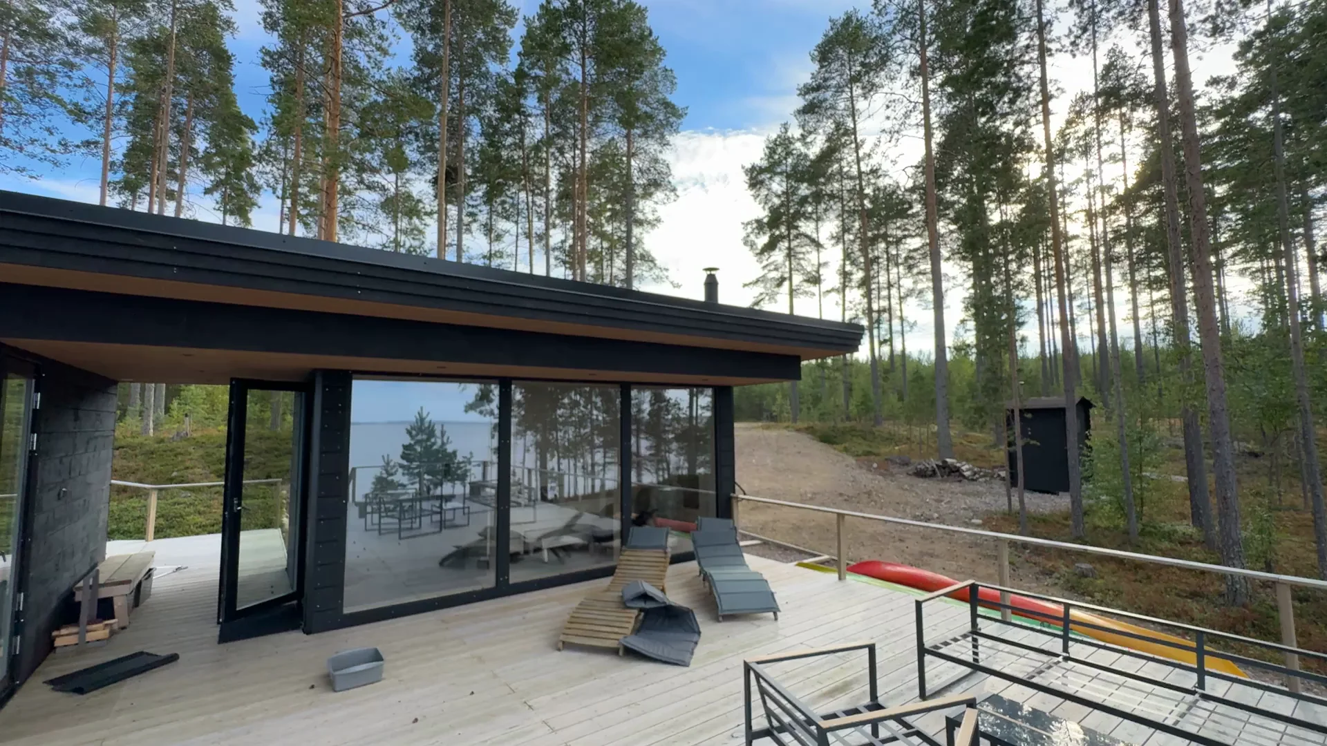 Villa Panorama Saimaa seen from its terrace, with pine trees and Lake Saimaa reflected in the glass